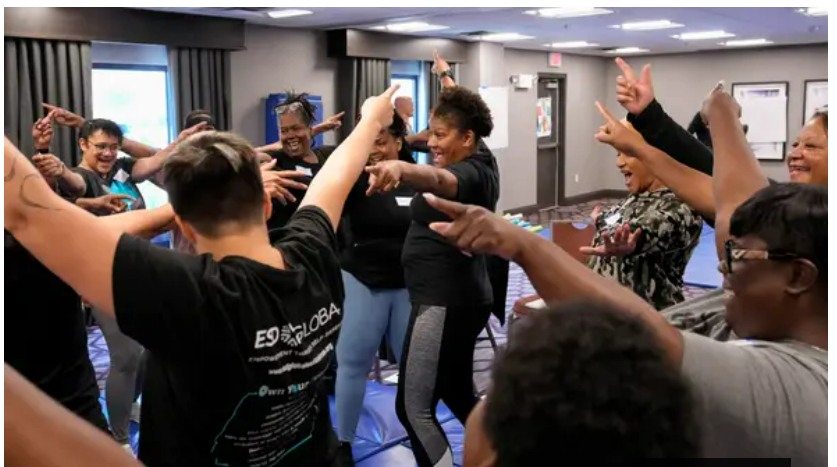 Group of Black women smiling and pointing at each other during a We Are Worth Defending empowerment self-defense training session.