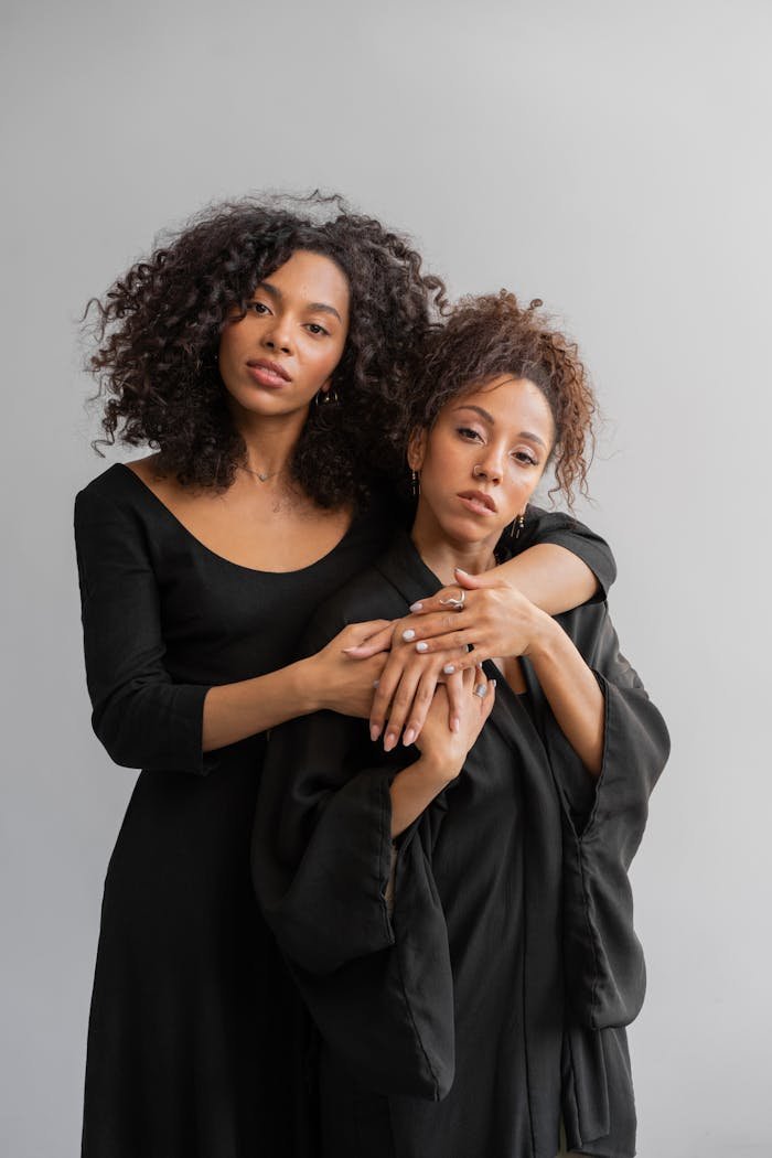 Two Afro-Haired Women in Black Robes Hugging